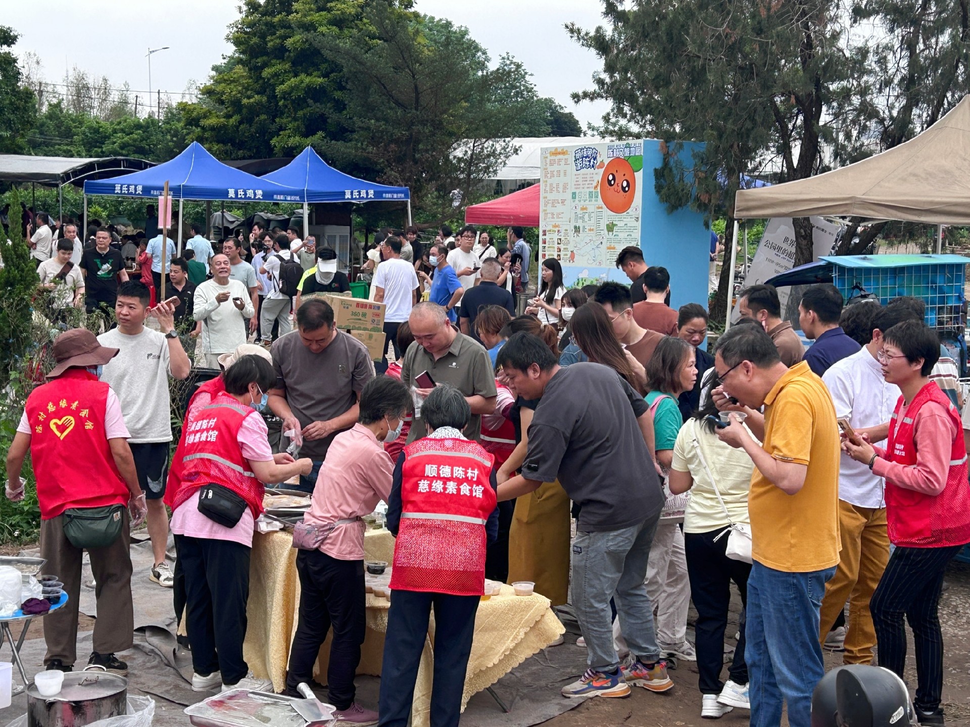 图为莫氏鸡煲店附近，义工们为游客免费赠送甜品小吃。兰航宇摄