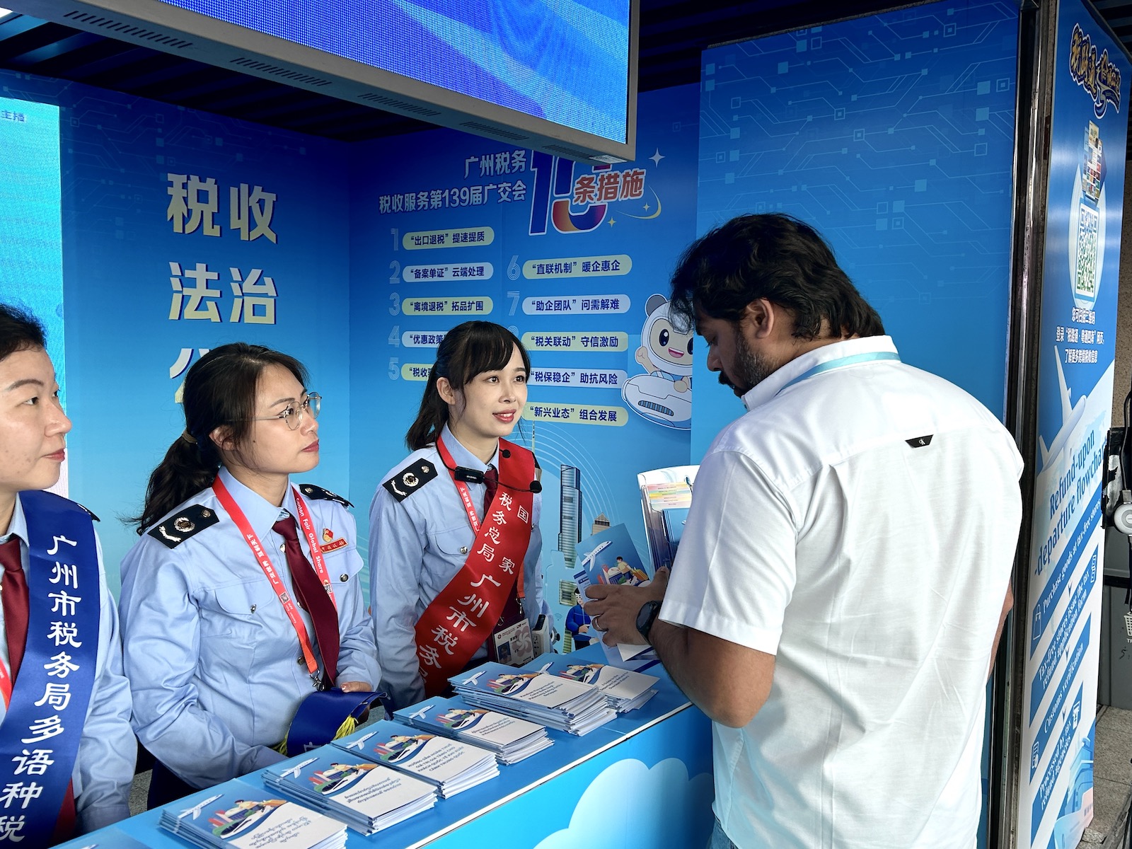 广交会现场，税收服务驿站工作人员为海外客商解答疑惑。实习生 兰航宇摄